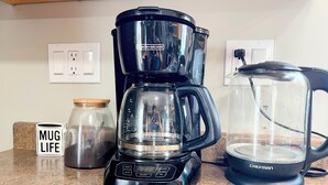 Une cuisine équipée d’une machine à café, d’un mixeur et d’un récipient en verre posé sur le plan de travail.