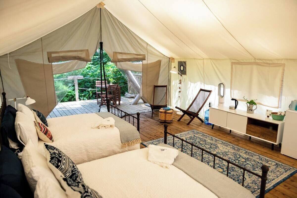 A tented accommodation with two beds, a dining area, and a kitchenette.