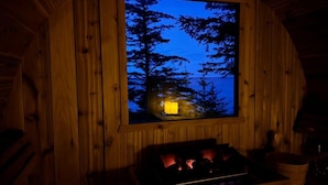 Interior de una cabaña de madera con ventana que da a un bosque.
