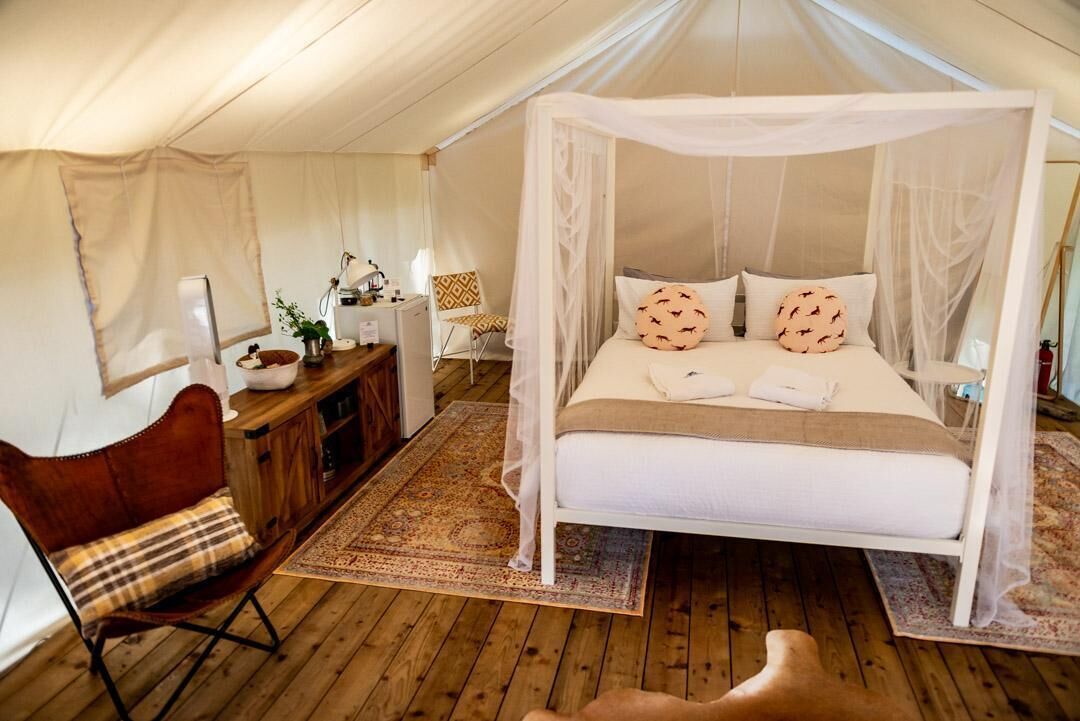 Ein Schlafzimmer mit einem Himmelbett, einem Holztisch, einem Stuhl und einem kleinen Tisch mit einer Lampe.