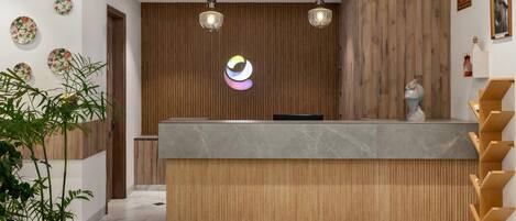 A reception area with a wooden panel wall, a marble counter, and two hanging pendant lights.