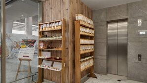 A wooden display stand with various packaged goods in a modern interior with a marble floor and an elevator.