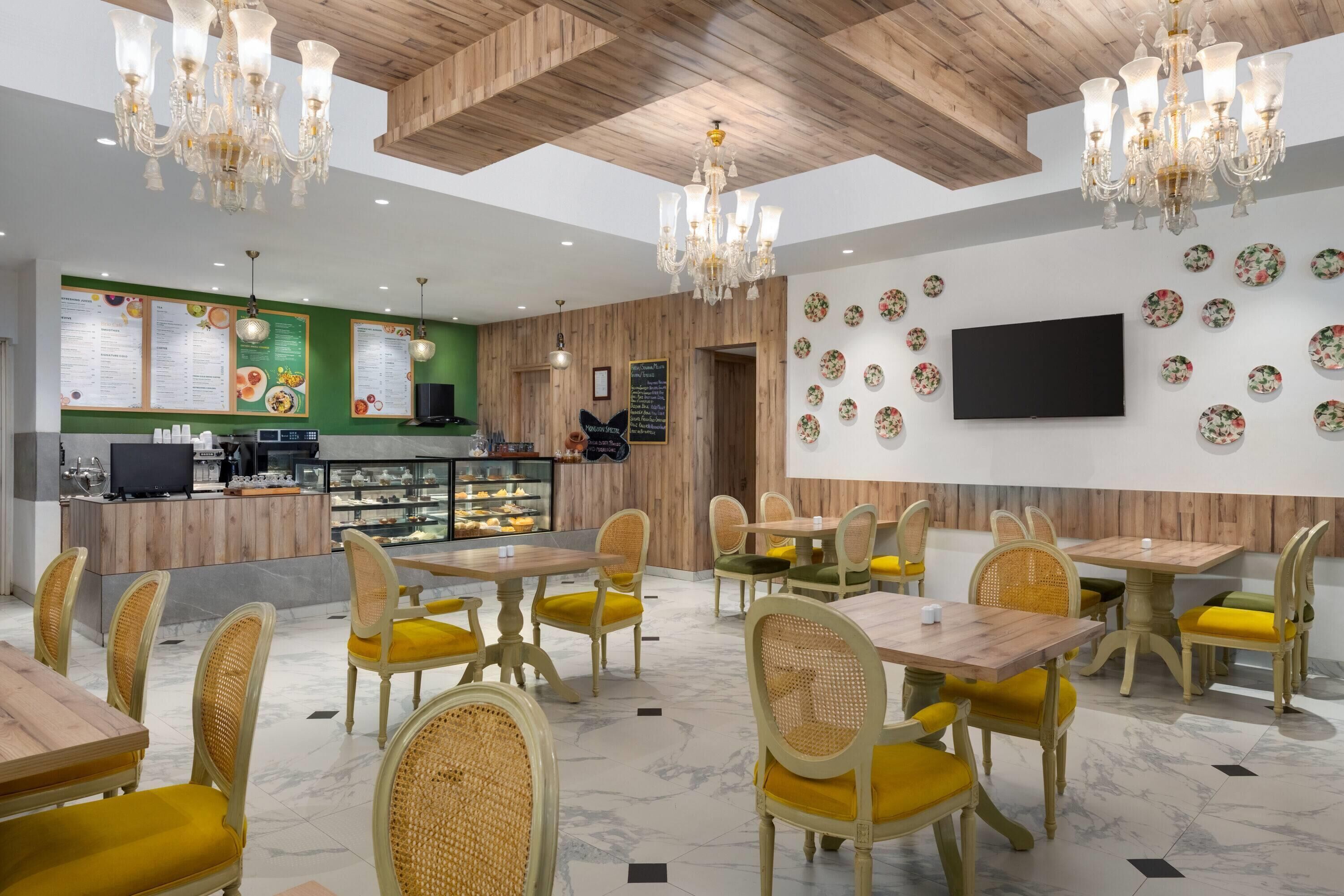 Un restaurant avec des poutres en bois au plafond, des lustres et un tableau affichant le menu sur le mur.