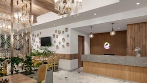 A modern reception area with a wooden reception desk, a chandelier, and a wall decorated with circular plates.