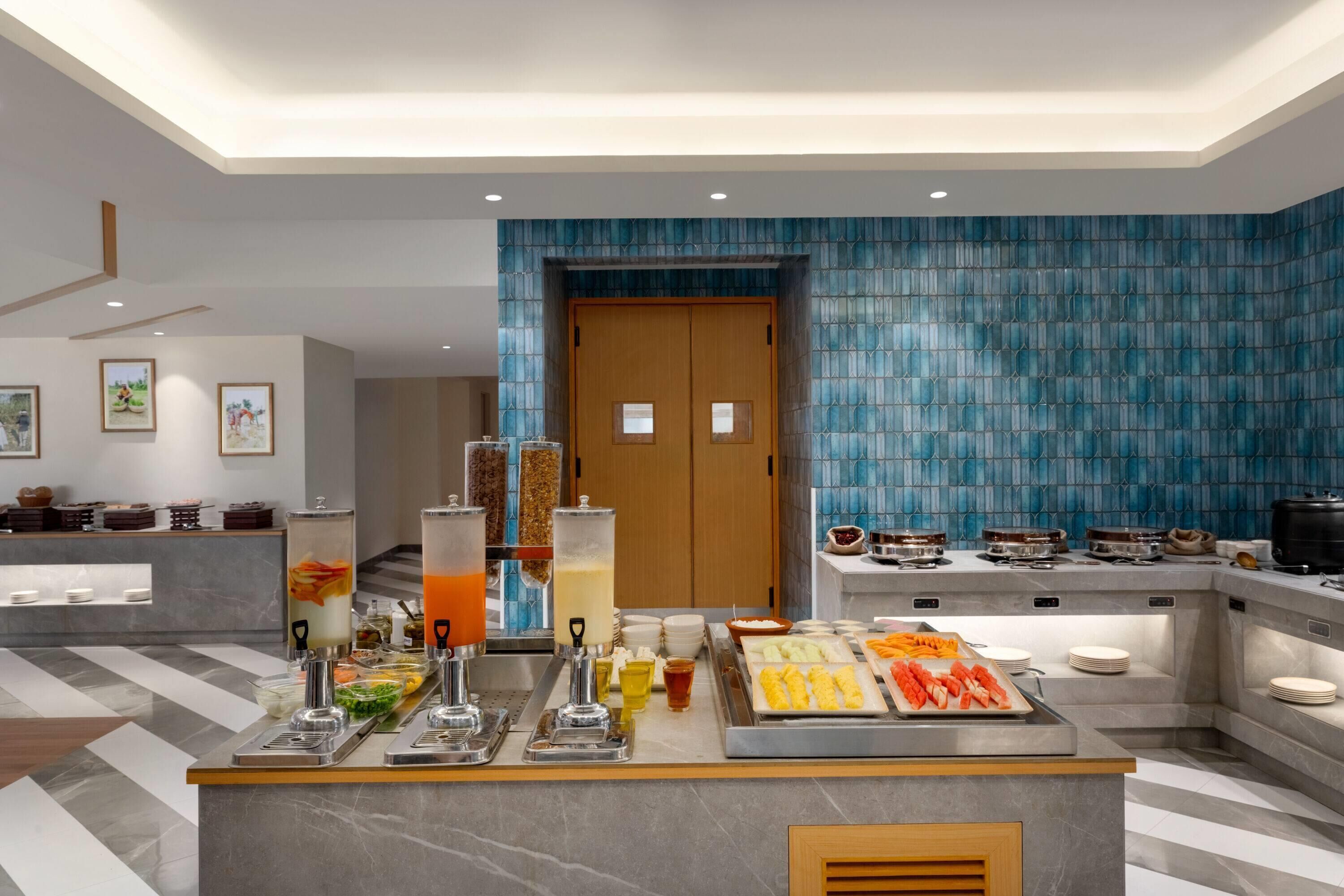 Un moderno vestíbulo de hotel con una zona de bufé que ofrece una variedad de alimentos y bebidas.