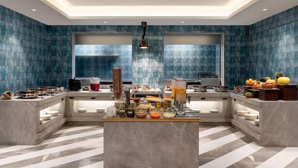 A modern kitchen with a central island, built-in appliances, and a blue-tiled backsplash.