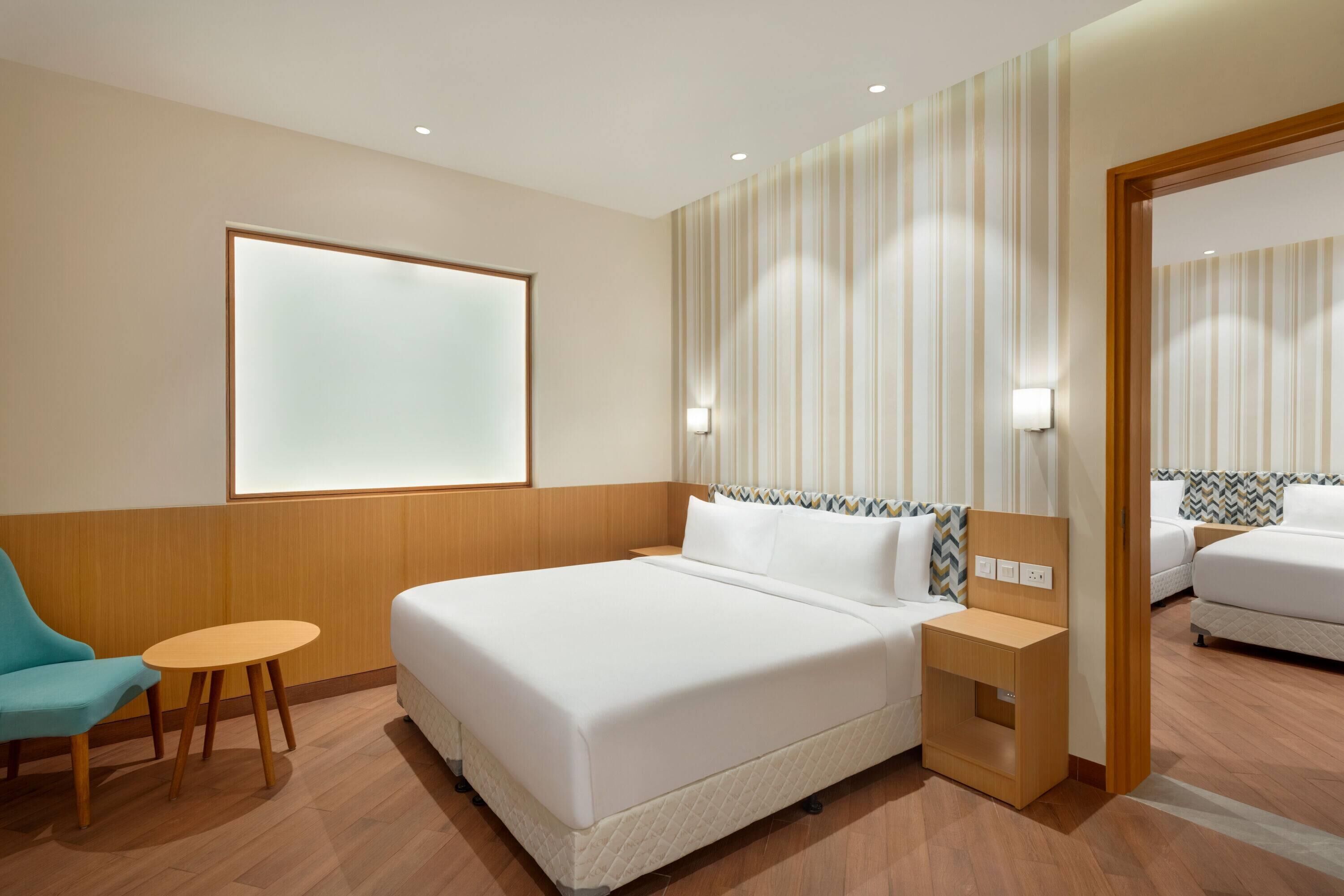 Une chambre d’hôtel avec un grand lit, une petite table, une chaise et un miroir.