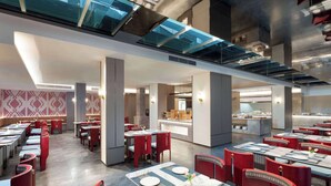 Un restaurante espacioso con techos altos, iluminación moderna y una combinación de asientos rojos y grises.