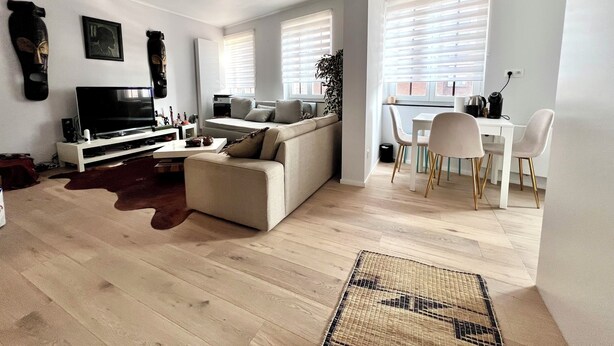 Una sala de estar moderna con sofá, televisor y comedor con sillas y mesa.