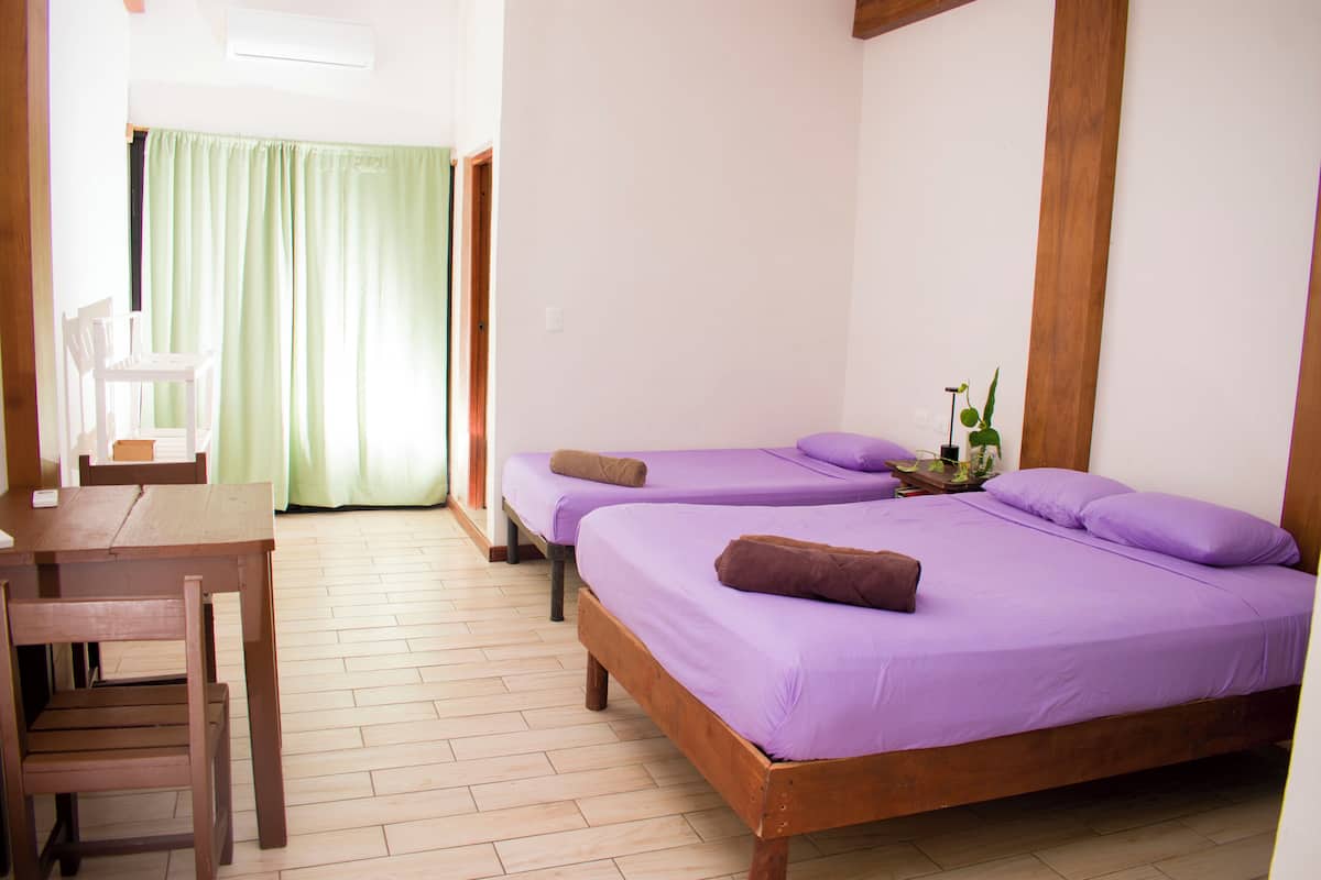 A room with two beds, a wooden desk, and a chair.