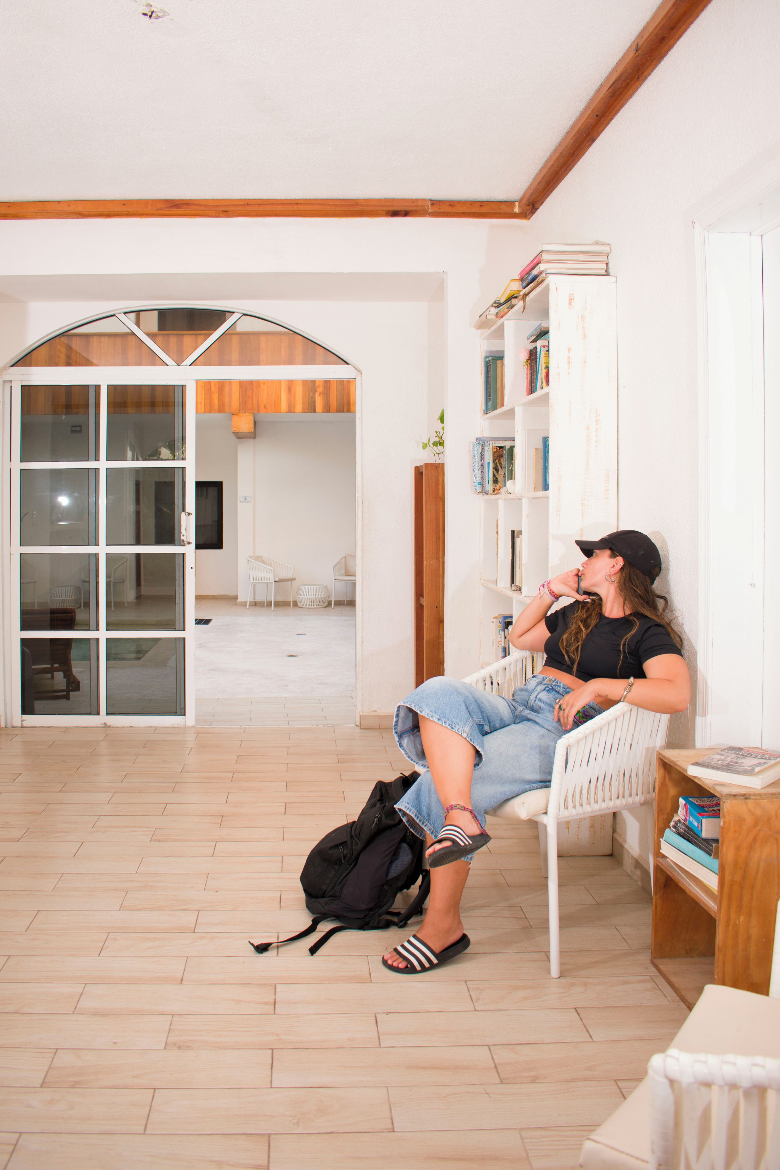 Una habitación con una silla blanca, una estantería y suelo de madera.