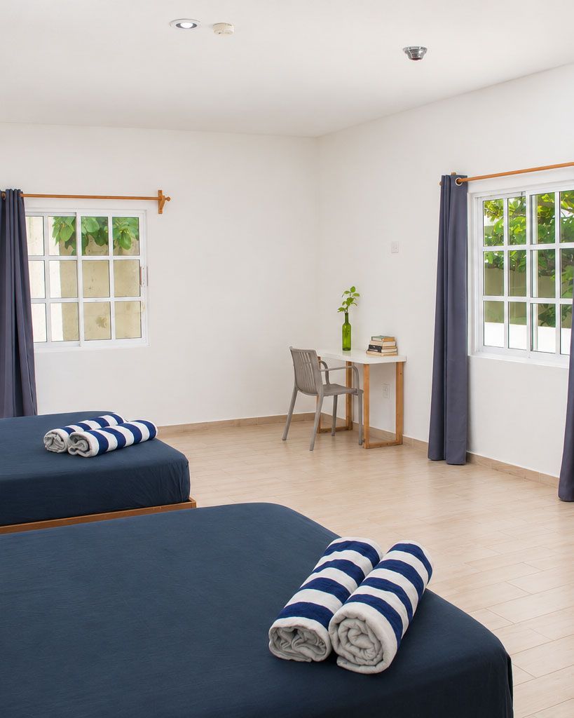 A room with two beds, a desk, and a chair.