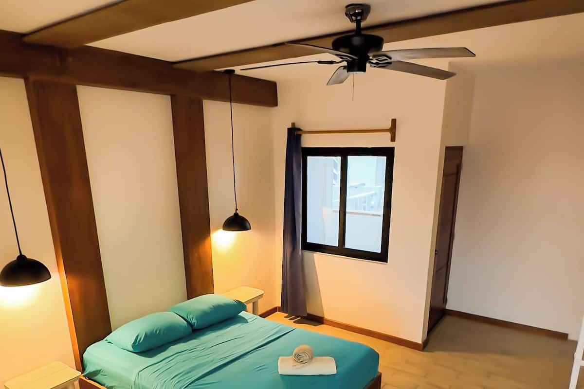 A bedroom with a bed, bedside tables, a ceiling fan, and a window.