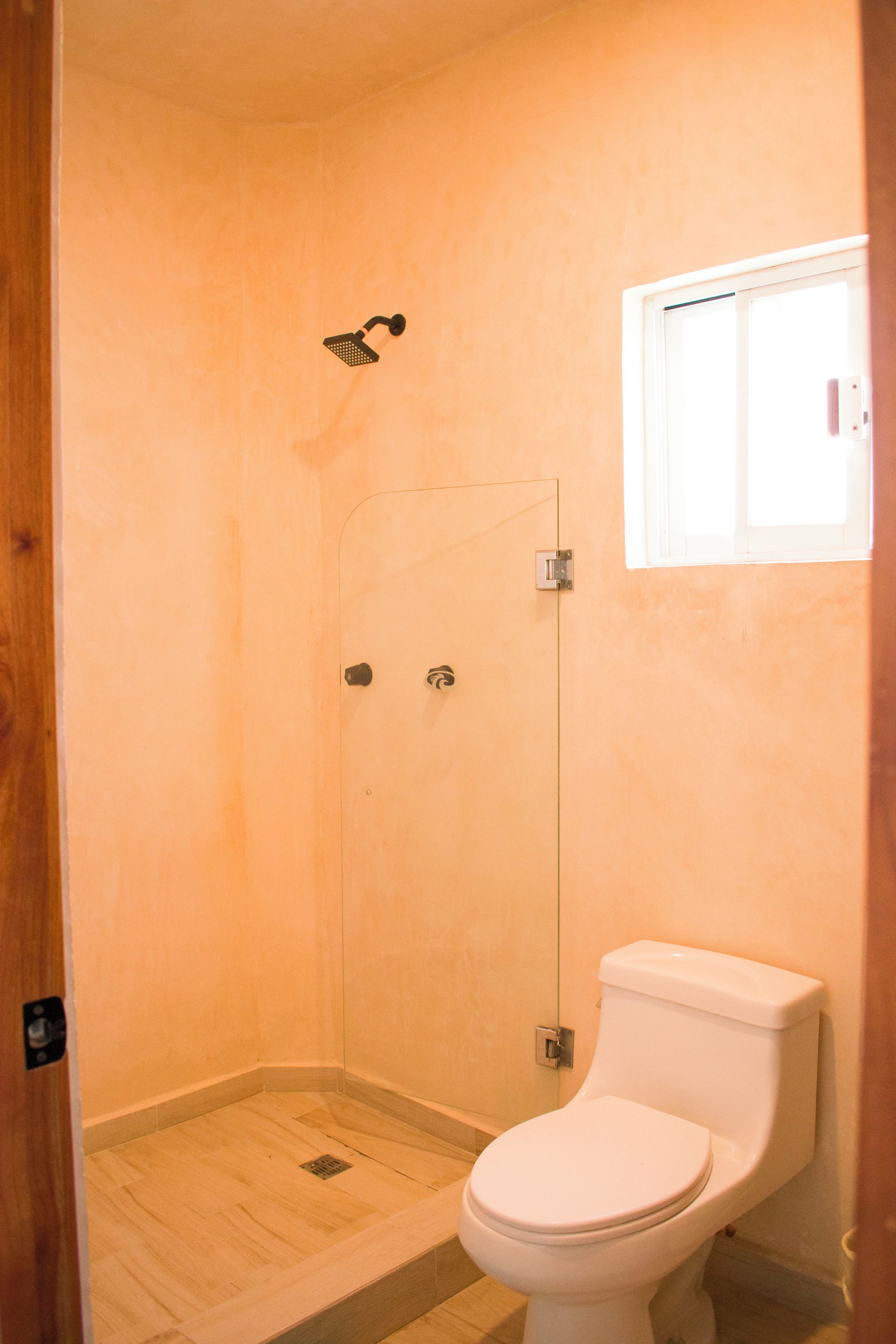 A small, enclosed shower area with a toilet and a window.