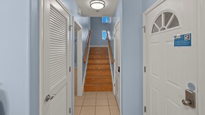 A hallway with a wooden staircase, white doors, and a sign indicating a 79-degree thermostat setting.