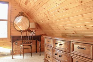 A wooden cabin interior with a wooden dresser, a chair, and a mirror on the wall. - Lakeside Log Cabin + Hot Tub (Danbury)