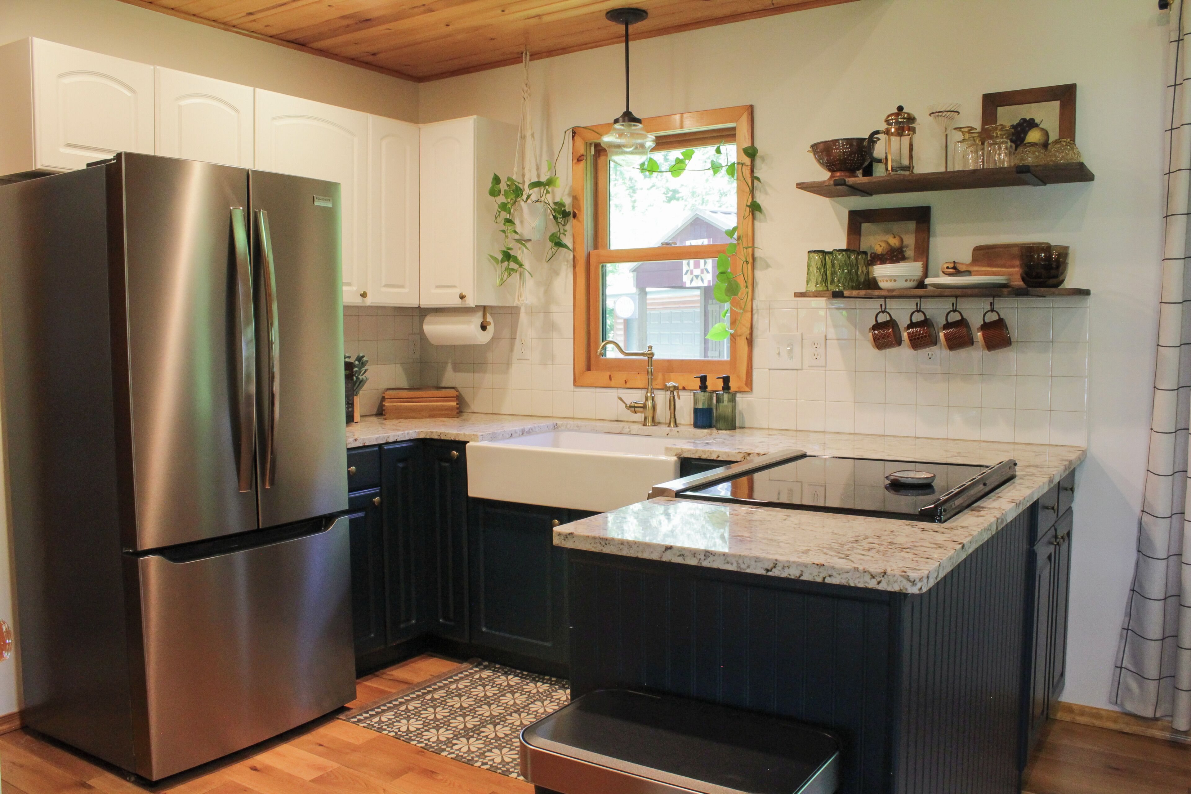 Una cocina moderna con refrigerador de acero inoxidable, horno empotrado, pileta con grifo de estilo rústico y ventana con vista al exterior.