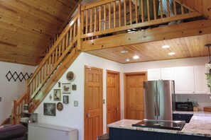 A kitchen with a stainless steel refrigerator, wooden cabinets, and a marble countertop.