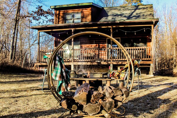 Stroll up to this charming cabin, featuring a central entrance and windows on either side, set amidst a secluded wooded area.