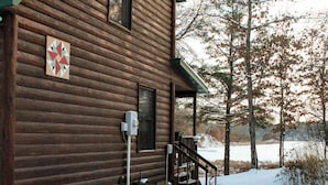 A wooden cabin with a covered porch and a snow-covered ground. - Lakeside Log Cabin + Hot Tub (Danbury)