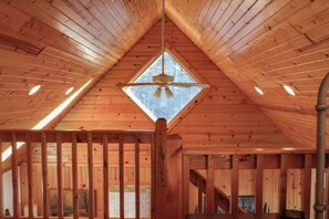 Cozy retreat with a rustic wooden ceiling, central skylight, and ceiling fan.