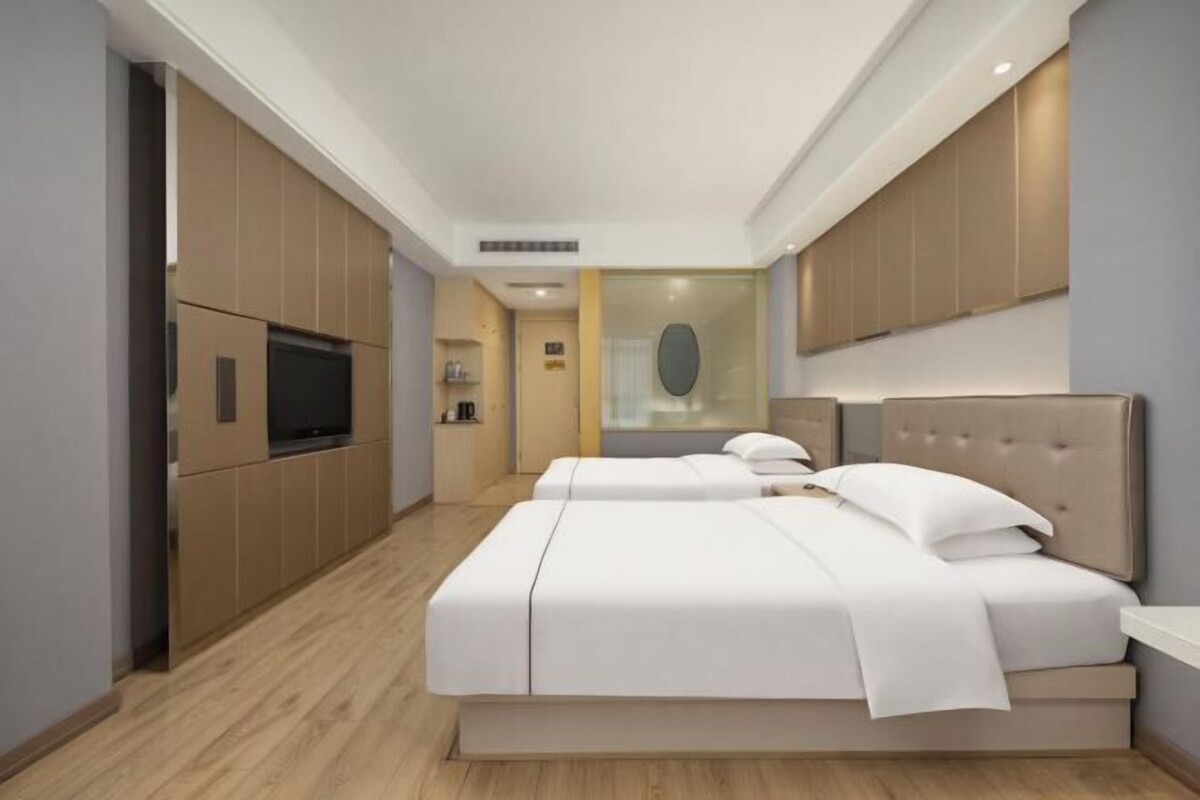 A modern hotel room with a large bed, a television, and built-in wardrobes.