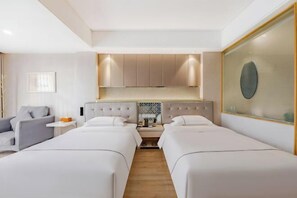 A hotel room with two single beds, a small sofa, a nightstand with a lamp, and a decorative wall piece. - Anqing Mingjia Hotel (Anqing)