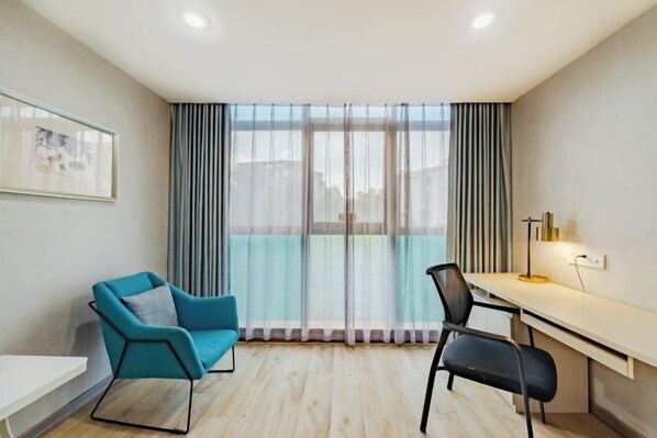 A modern room with a desk, two chairs, a large window with curtains, and a framed picture on the wall. - Anqing Mingjia Hotel (Anqing)