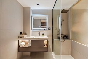 A modern bathroom with a glass-enclosed shower, a vanity with a mirror, and a built-in shelf for toiletries. - Anqing Mingjia Hotel (Anqing)
