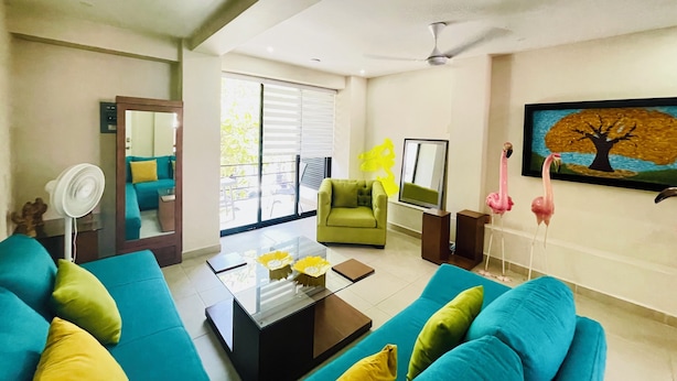 A living room with a sofa set, a coffee table, a TV, and a painting on the wall. - Charming, fully appointed 1-bedroom apartment in PV’s amazing Zona Romantica (Puerto Vallarta)