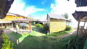 A colorful outdoor area with a hammock, a small structure labeled 'COLCHA', and a grassy lawn. - Graces Place Cool Spot  (Corn Islands)