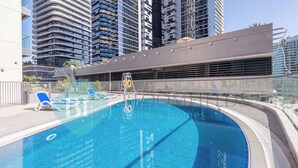 A swimming pool with lounge chairs, surrounded by high-rise buildings. - Bloomfields Luxurious 1BR Down Town (Dubai)