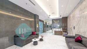A modern hotel lobby with a marble floor, grey sofas, and a reception desk. - Bloomfields Luxurious 1BR Down Town (Dubai)