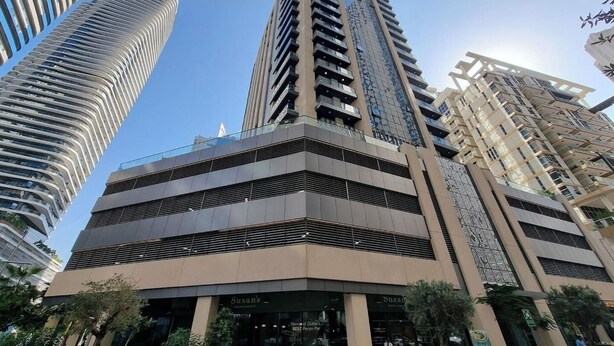 A multi-story building with a modern architectural design, featuring a prominent entrance with signage. - Bloomfields Luxurious 1BR Down Town (Dubai)
