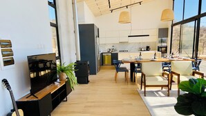 Une cuisine moderne dotée d’un îlot central, d’un coin repas avec une table et des chaises en bois, et d’une grande fenêtre offrant une vue sur l’extérieur.