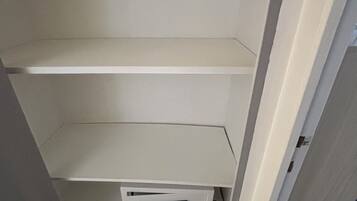 Een witte kast met drie vakken, waarvan één een zwart elektronisch apparaat bevat.