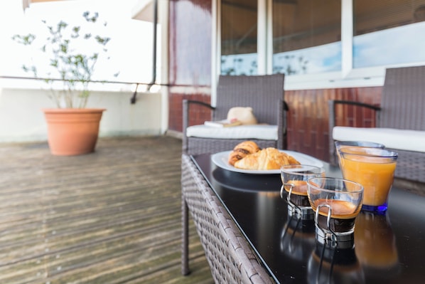 A table with croissants, coffee, and orange juice on a balcony.