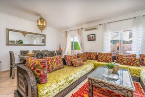 Un salon comprenant un ensemble de canapés, une table à manger avec des chaises, une table basse en verre et un grand miroir mural.