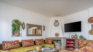 A living room with a sofa set, a flat-screen TV, decorative wall art, and a fireplace. - #298 Villas Luz H by Home Holidays (Albufeira)