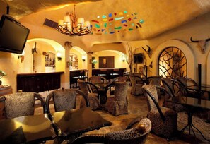 Um espaço de bar com televisão, tetos em arco e mobiliário com estampa de leopardo.