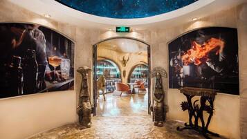 Um hall de hotel com teto estrelado, um arco central e duas grandes pinturas nas paredes.