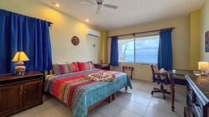 Una camera d'hotel con un letto, una scrivania, una sedia e vista sul mare.
