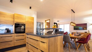 Eine moderne Küche mit Holzausstattung, einer zentralen Kochinsel und einem Essbereich mit einem roten Stuhl und einem Fernseher.