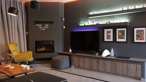 A modern living room with a flat-screen TV, a fireplace, a yellow armchair, and a wooden coffee table. - One Luxury House 
Above The Sea .... (Myrthianos Plakias)