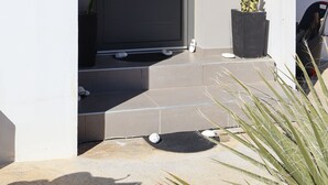 A modern building entrance with a dark door, a welcome sign, and a potted plant. - One Luxury House 
Above The Sea .... (Myrthianos Plakias)
