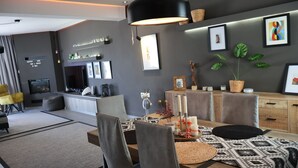 A modern living room with a dining area, grey walls, a black ceiling light, and a TV. - One Luxury House 
Above The Sea .... (Myrthianos Plakias)