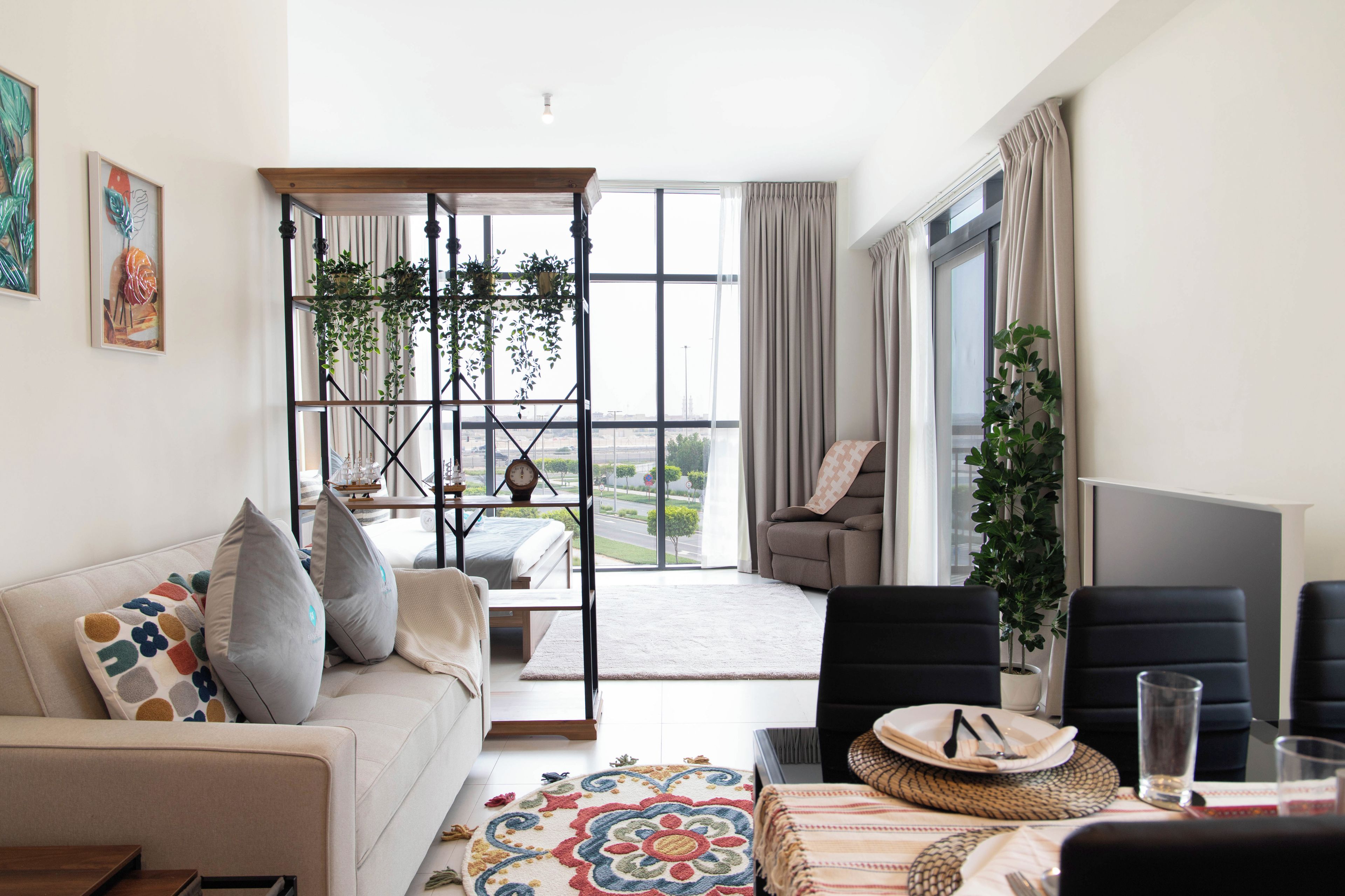 Ein modernes Wohnzimmer mit einer Couch, einem Esstisch und einem großen Fenster.