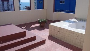 Une terrasse sur le toit avec un jacuzzi, une plante en pot et une vue sur l’océan.