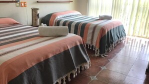 Une chambre avec deux lits, chacun étant équipé d’une literie à rayures et d’un oreiller.