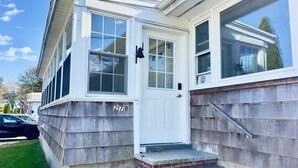 A two-story house with a white exterior, a brick entrance, and a number '27B' displayed on the front wall. - Cozy 2-bedroom, 1-bathroom condo,  two short blocks from the beach! (Old Orchard Beach)